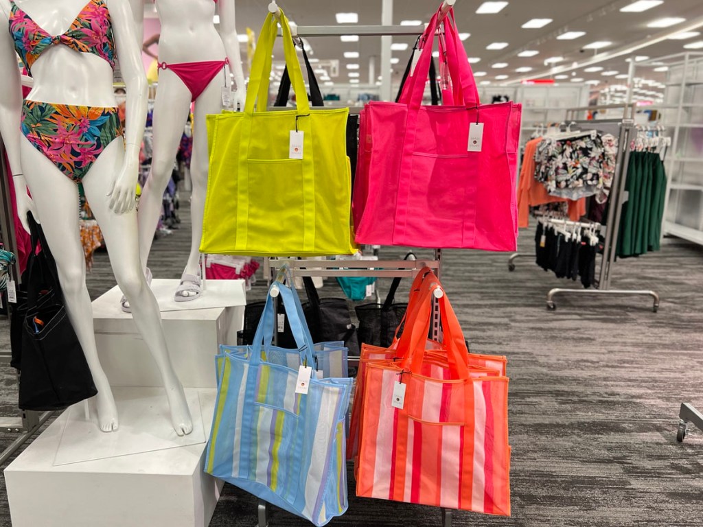 yellow, pink, blue and orange totes hanging on display at target store