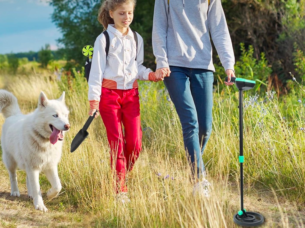 parent and child walking down with metal detector on trail