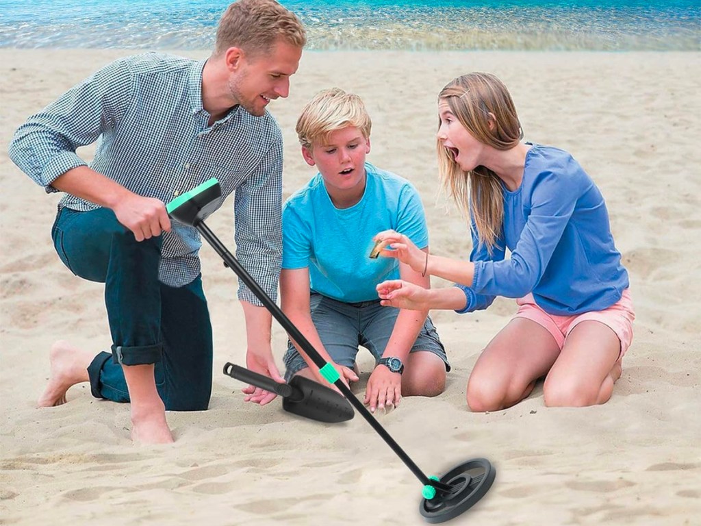 dad and two kids using metal detector at beach