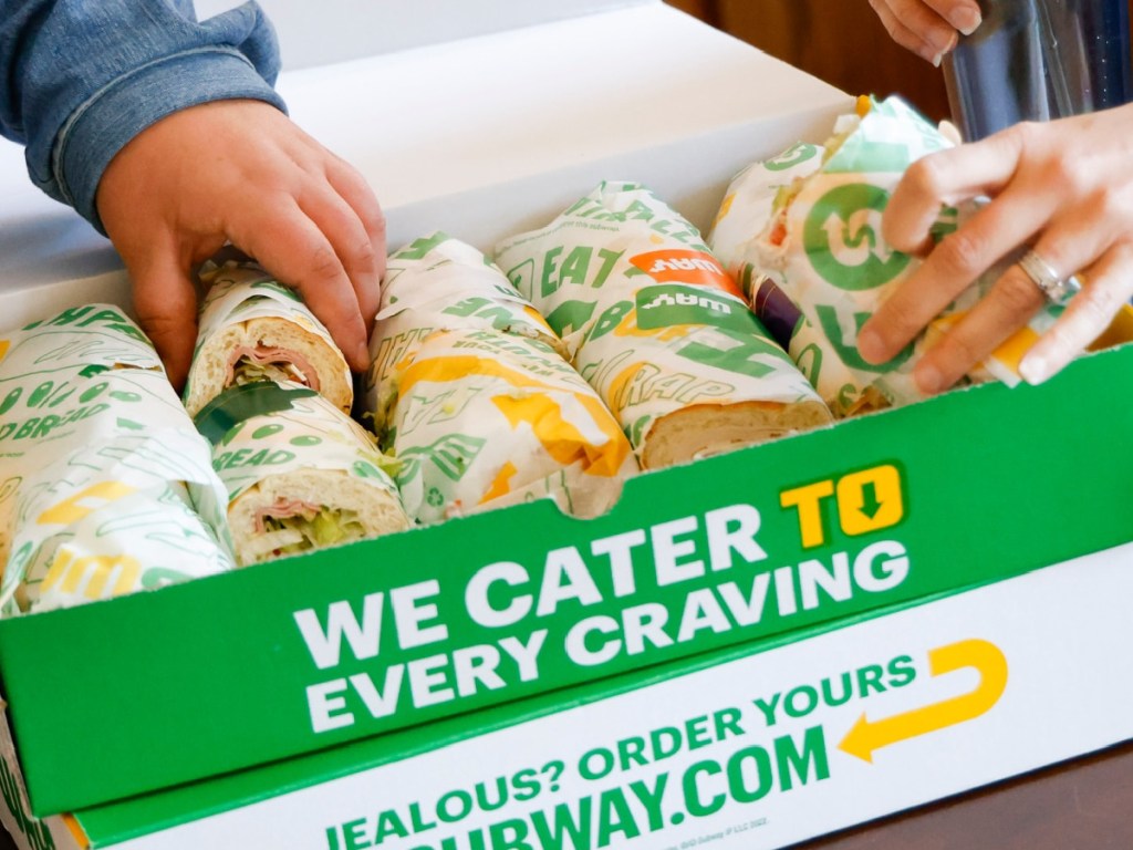 people putting food into subway catering box