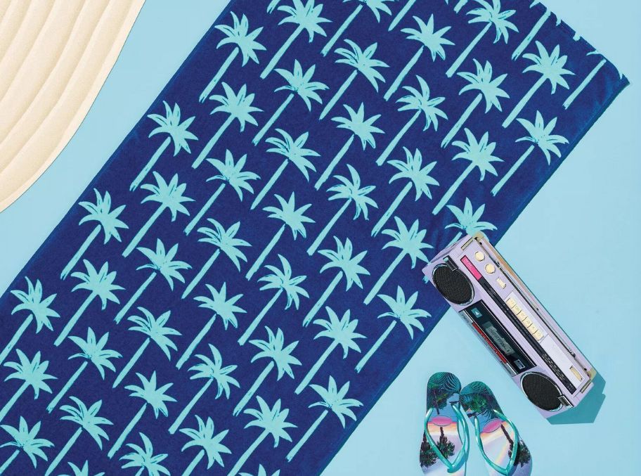 a blue beach towel with aqua colored palm print