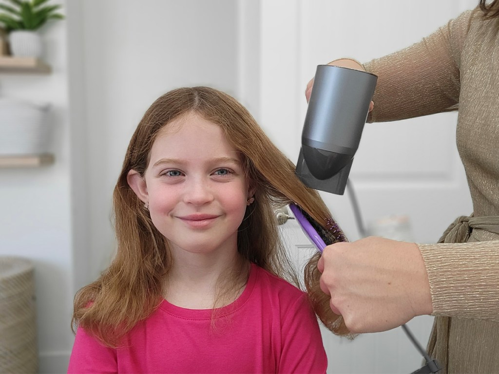 woman using hair dryer on girls hair