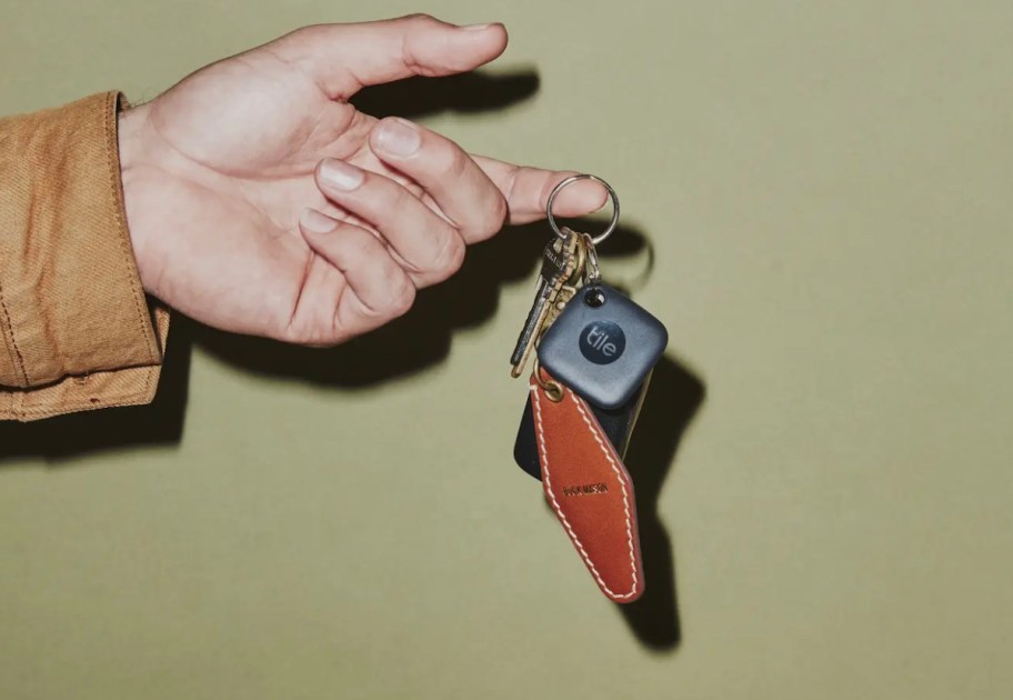 hand holding keys on keychain with tile mate bluetooth tracker