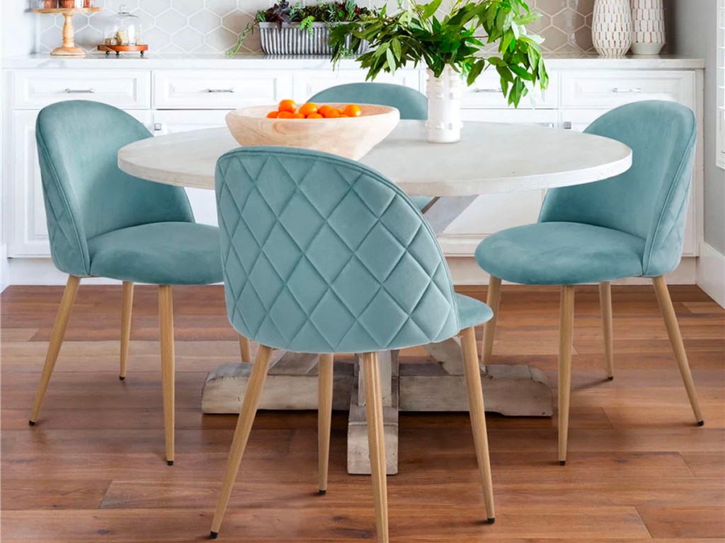 4 teal velvet dining chairs around white dining table