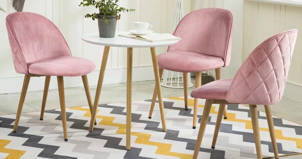 3 pink velvet chairs around small white end table