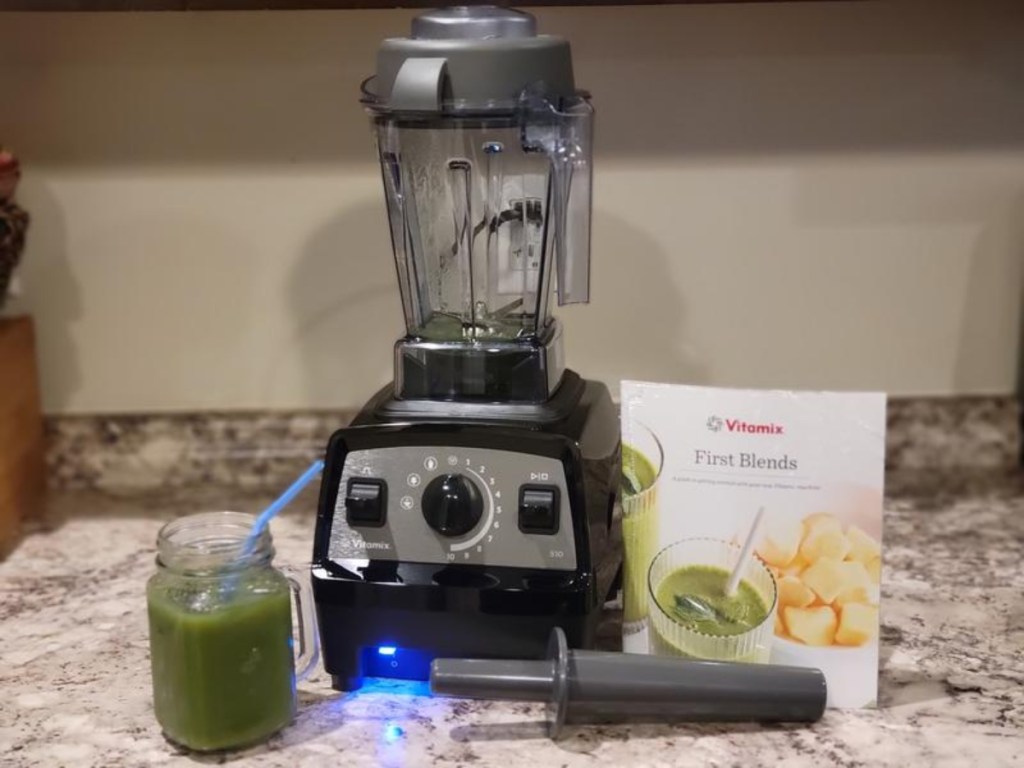 Vitamix on counter next to instruction manual and green smoothie