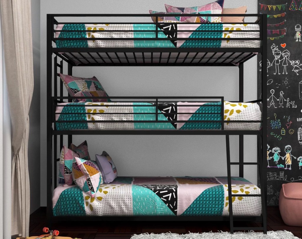 black triple bunk bed against a gray wall with colorful comforters and pillows on each mattress