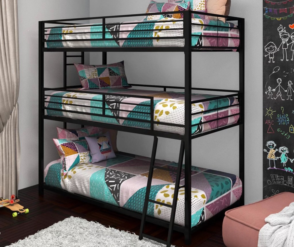 black triple bunk bed against a gray wall with colorful comforters and pillows on each mattress