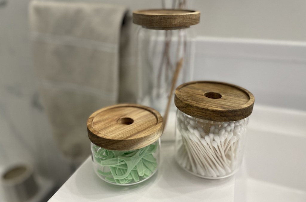 various clear and wood glass jar sets on bathroom sink