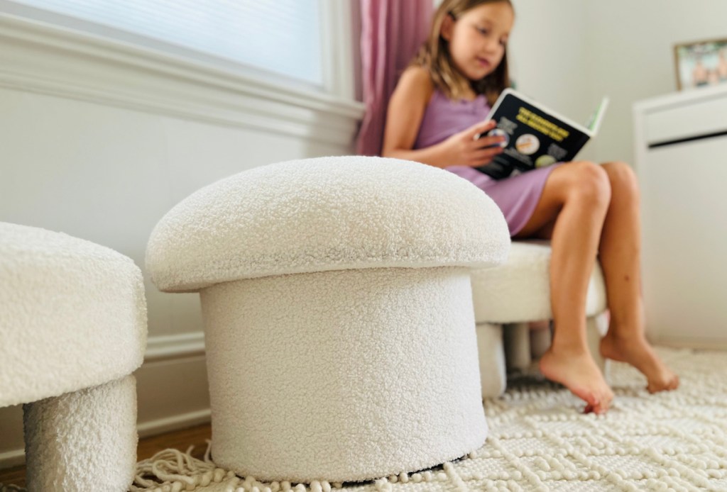 white mushroom ottoman next to girl in chair reading book