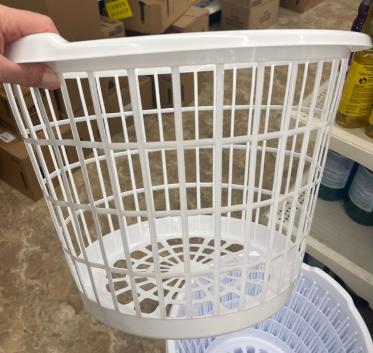 a womans hand holding a white plastic storage basket