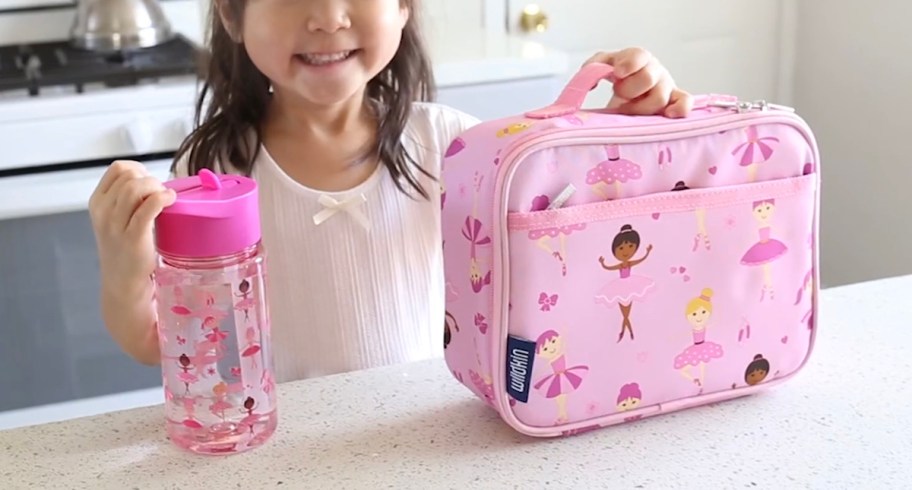 girl holding pink water bottle and princess ballerina lunch box 
