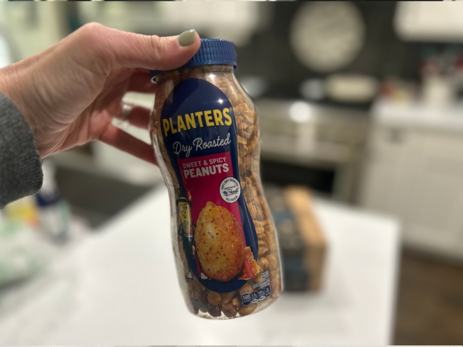 woman holding bottle of Planters Sweet & Spicy Peanuts