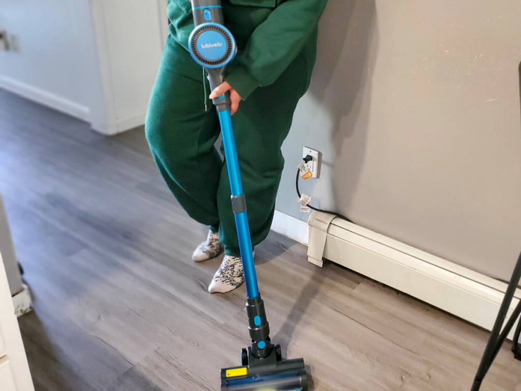 woman using a vacuum on her hardwood floors