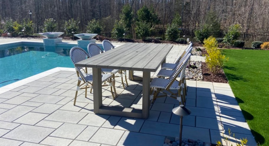wood outdoor dining table by pool 