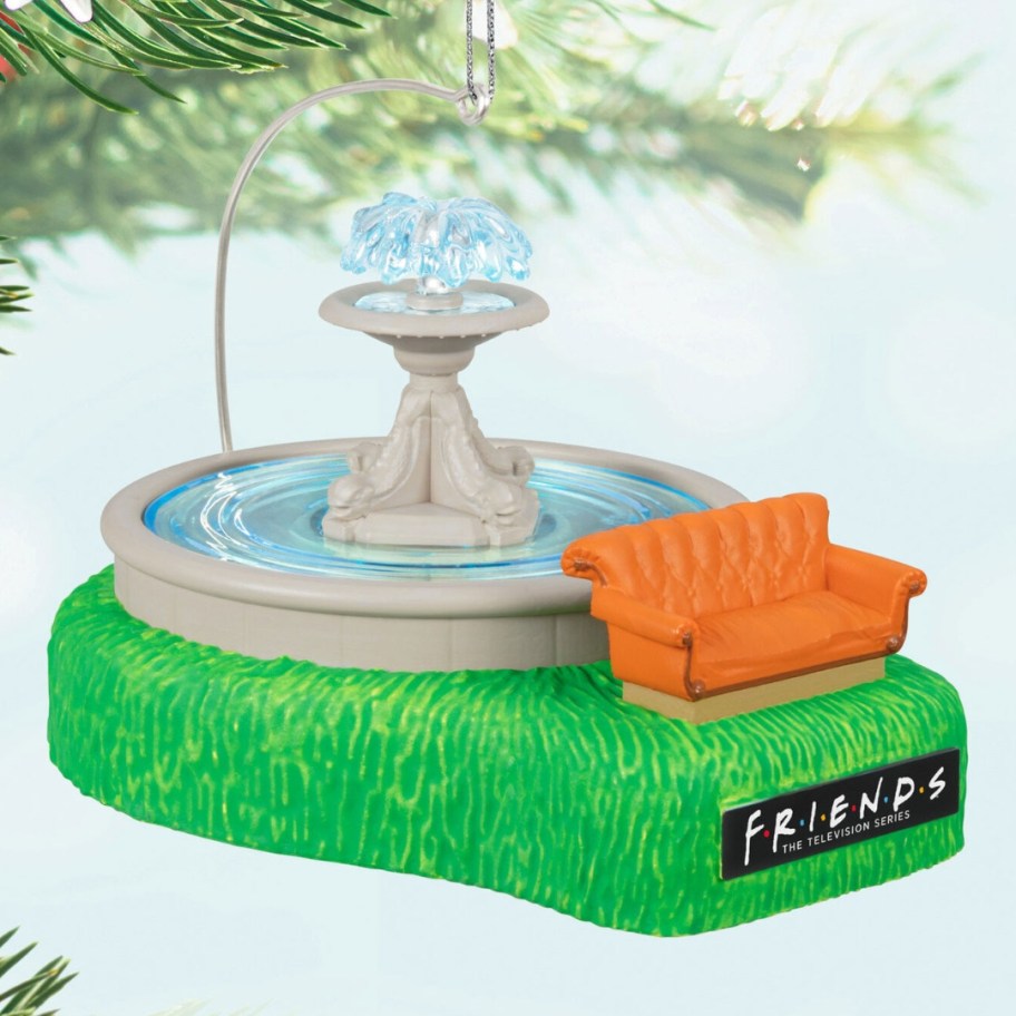 a Friends Christmas ornament hanging from a tree limb with the fountain and orange couch