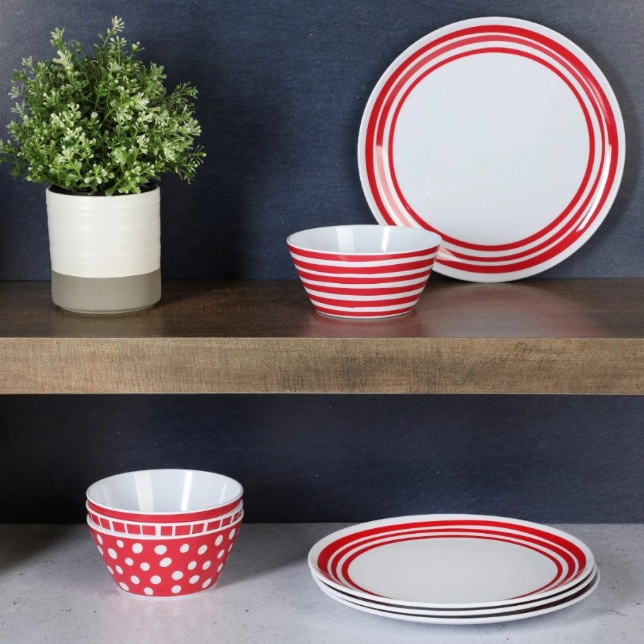 red and white melamine dinnerware plates and bowls on shelf and counter next to a plant
