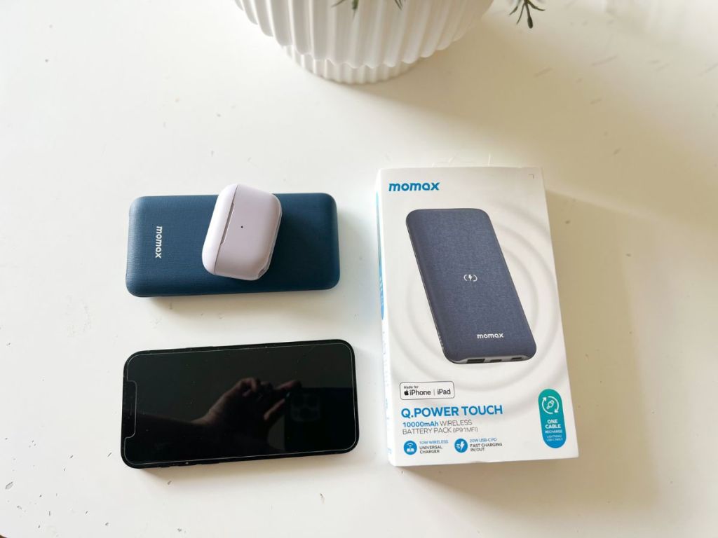 MOMAX Wireless Portable Charger shown with phone, Airpods and product box