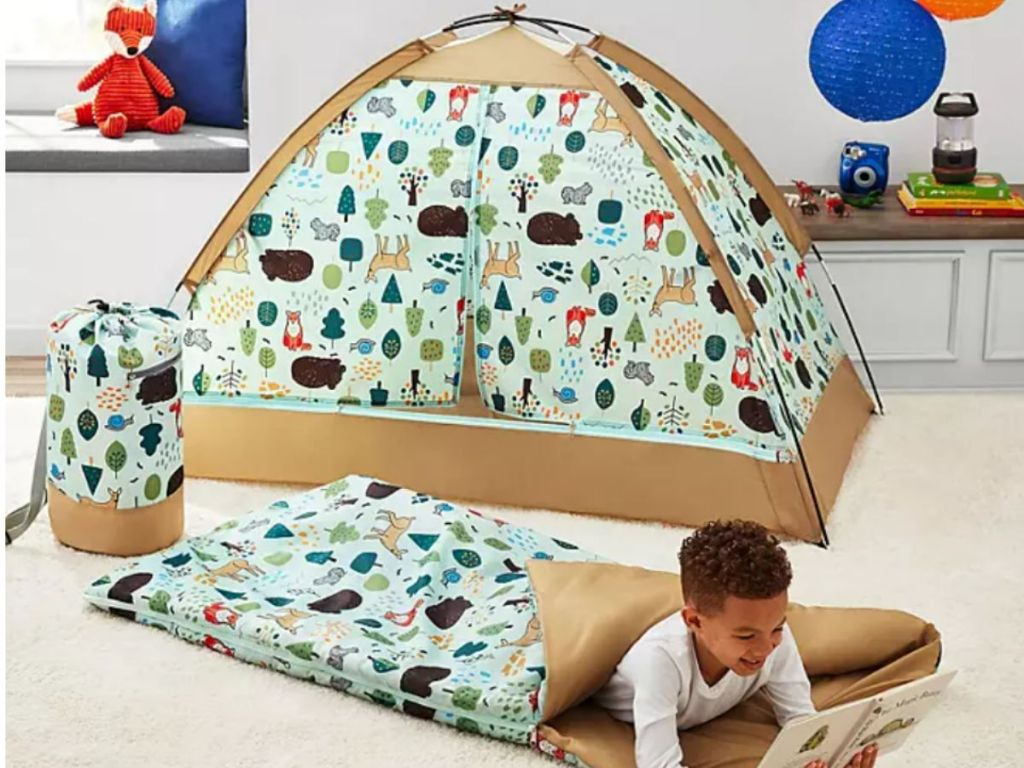 Member's Mark Kids' 3-Piece Slumber Set shown set up with indoor tent, sleeping bag and carry bag in Woodland with little boy inside sleeping bag