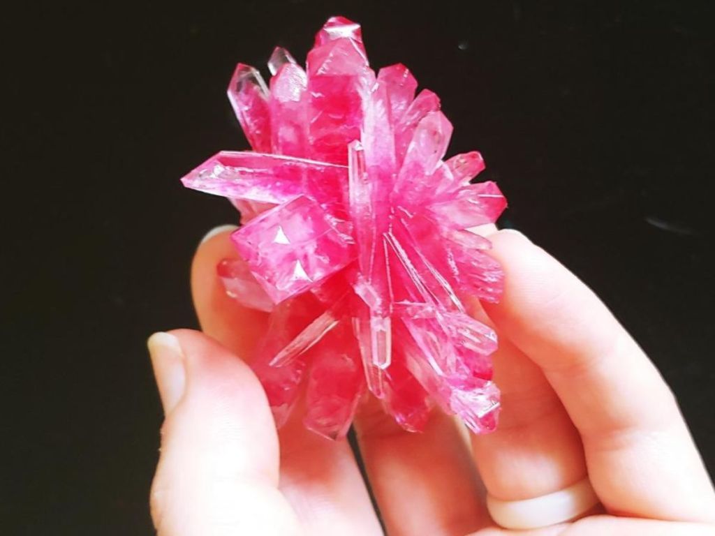 Hand holding a dark pink crystal
