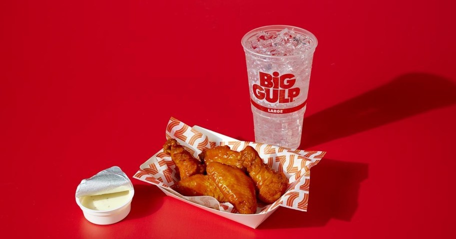 chicken wings, dip, and fountain soda on a red background