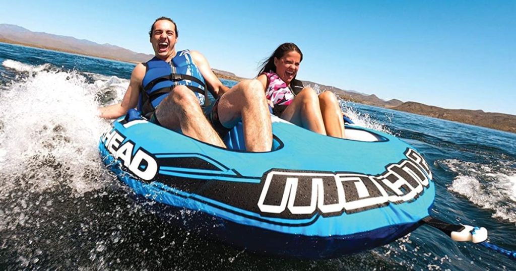 Woman and a man riding in a Airhead Mach 2, 1-2 Rider Towable Tube for Boating in the water
