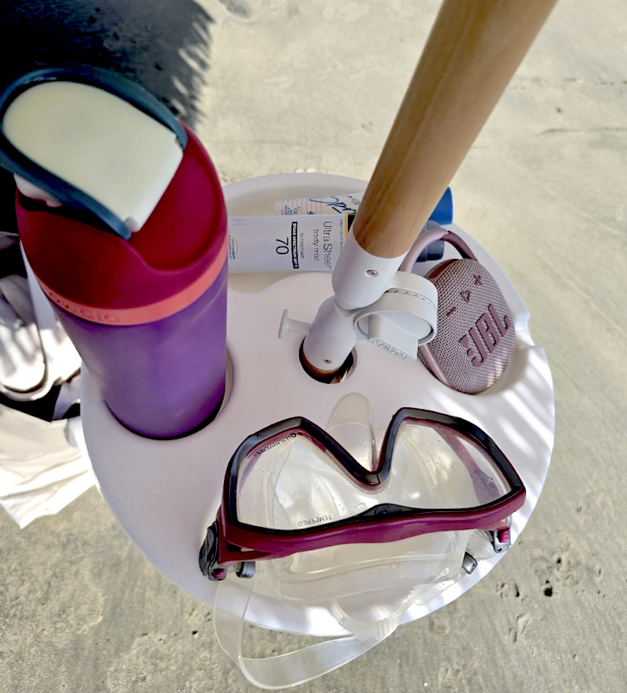 close up of white umbrella tray with various beach essentials on top