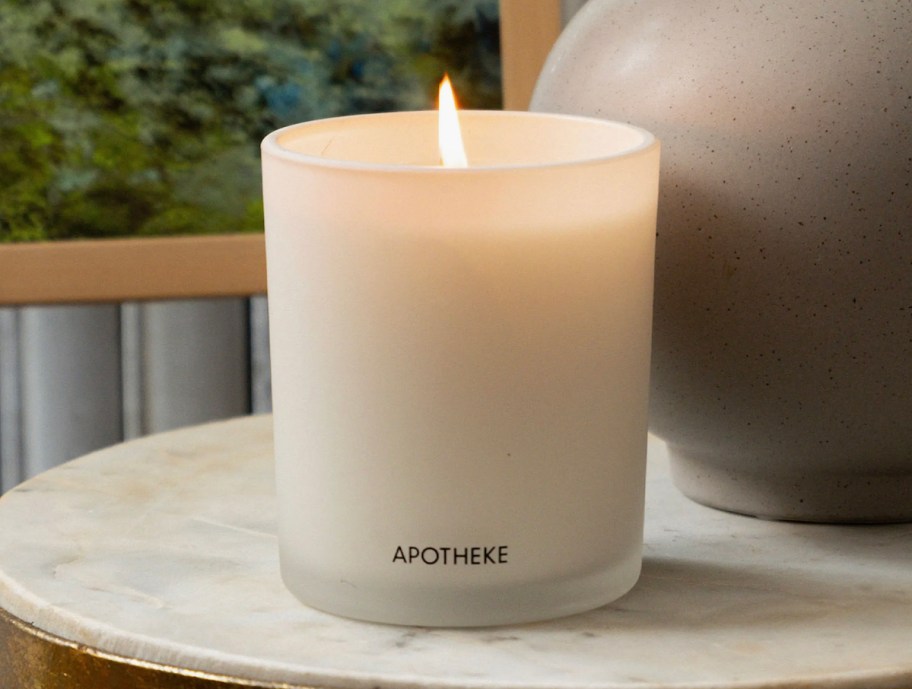 APOTHEKE candle with flame on marble side table