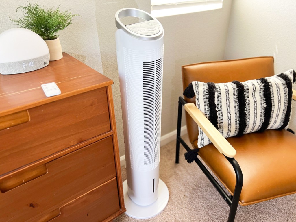 white tower fan next to dresser and accent chair