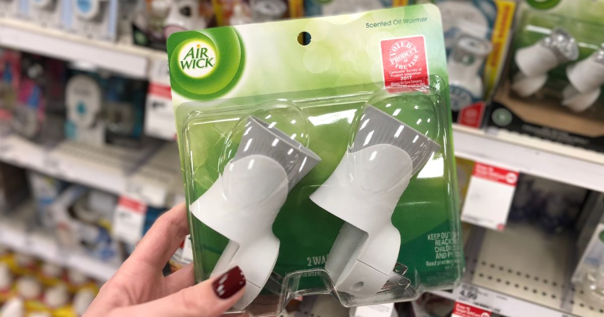 A womans hand displaying a 2 pack of airwick scented oil warmers on a target store aisle