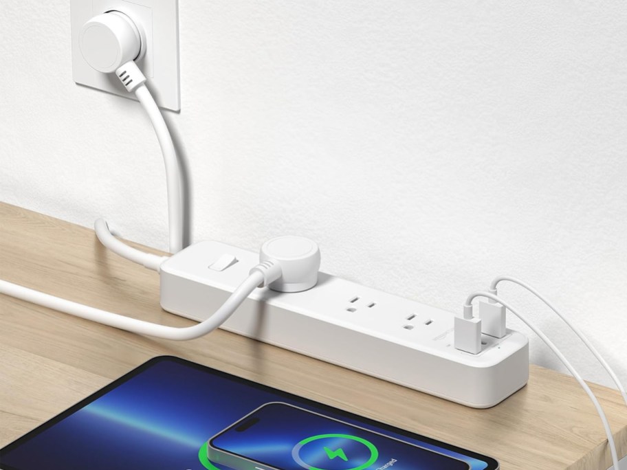 white power strip plugged into wall with tablet and phone plugged in and charging