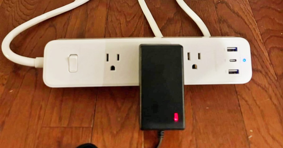 white power strip on floor with large black plus plugged in