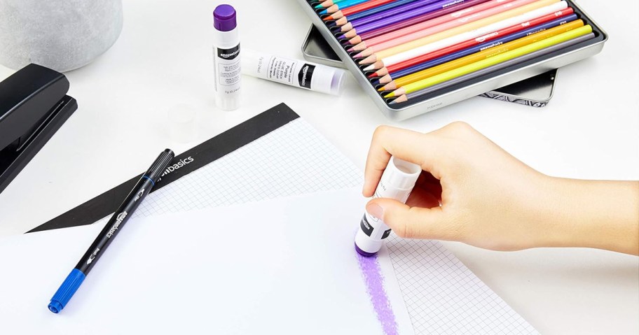 person using purple glue stick on piece of paper