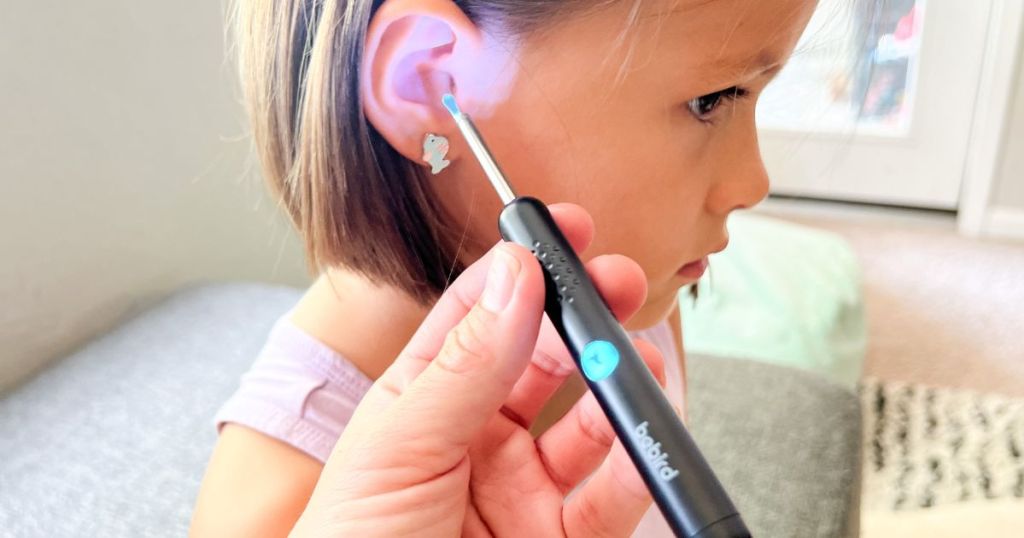 person with ear removal wand near girls ear