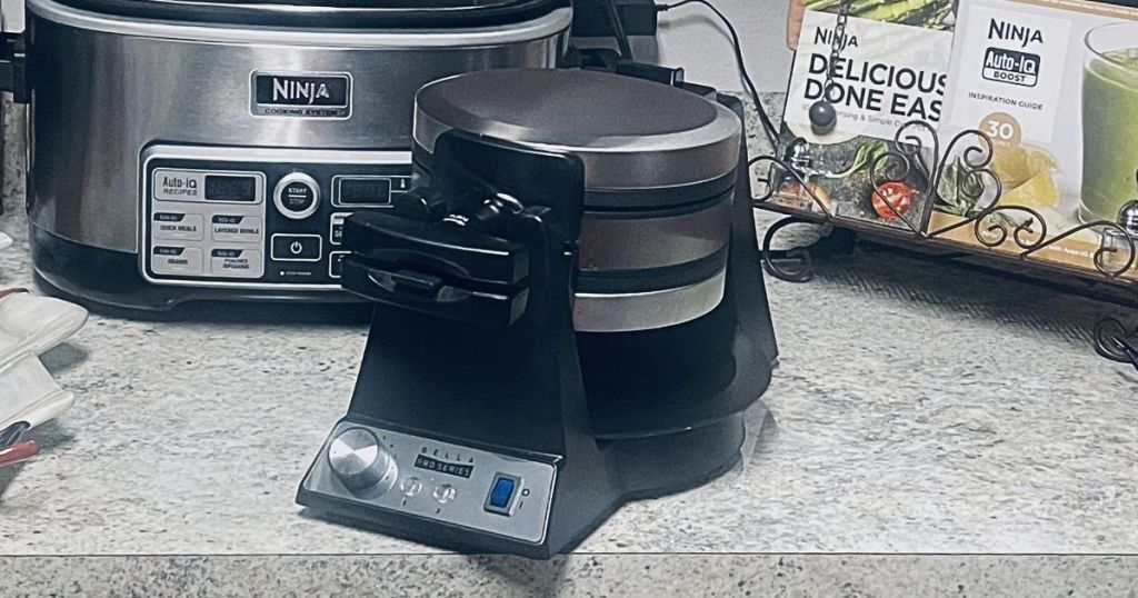 Bella flip waffle maker on counter with ninja crockpot and recipes in the back