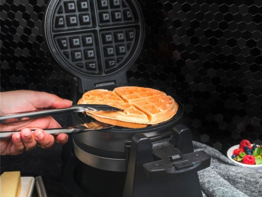 hand using tongs to take waffle off waffle maker