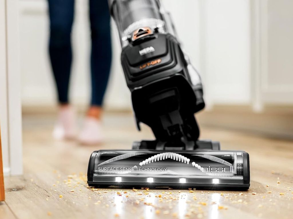 person vacuuming crumbs from hardwood floor