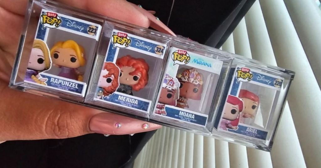 A hand holding 4 small Bitty Pops Disney Princesses