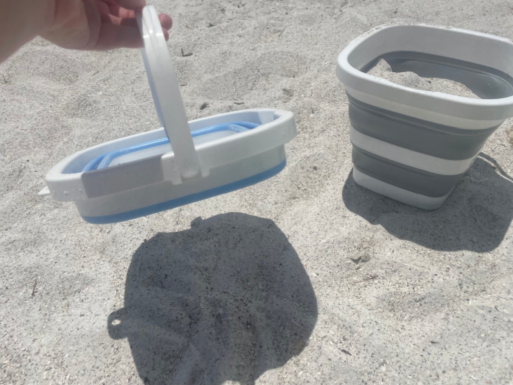 hand holding a collapsible bucket at the beach