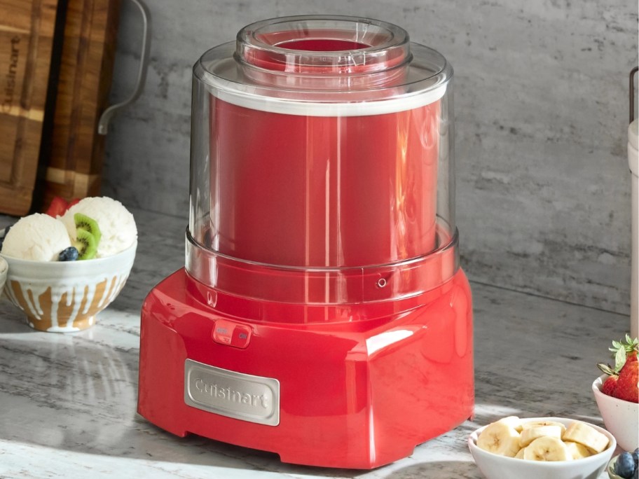 red Cuisinart ice cream maker on a kitchen counter next to a bowl of ice cream