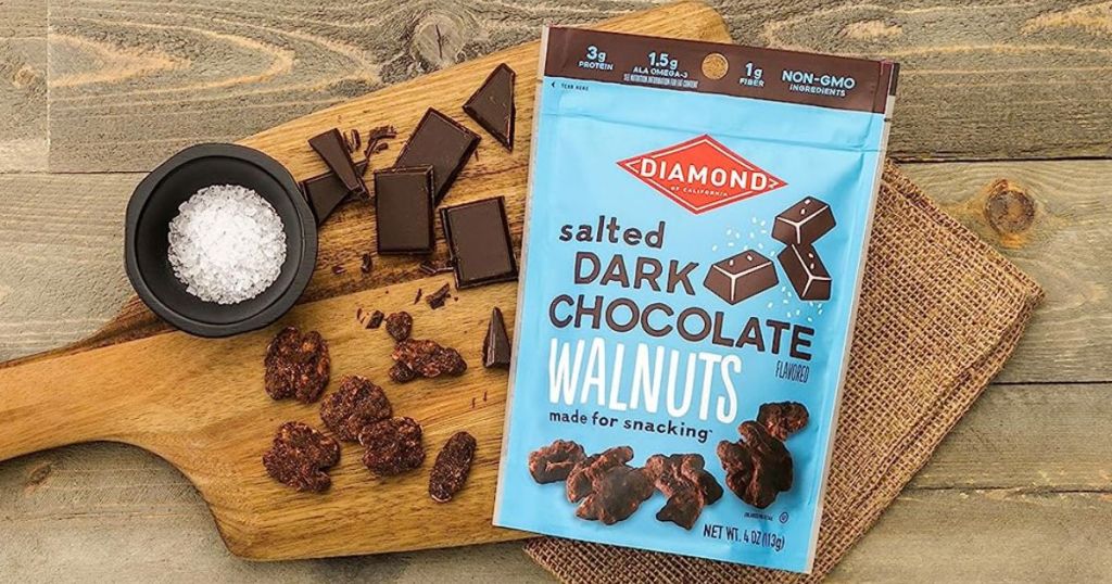 Diamond of California Salted Dark Chocolate Walnuts on a cutting board next to dark chocolate and salt