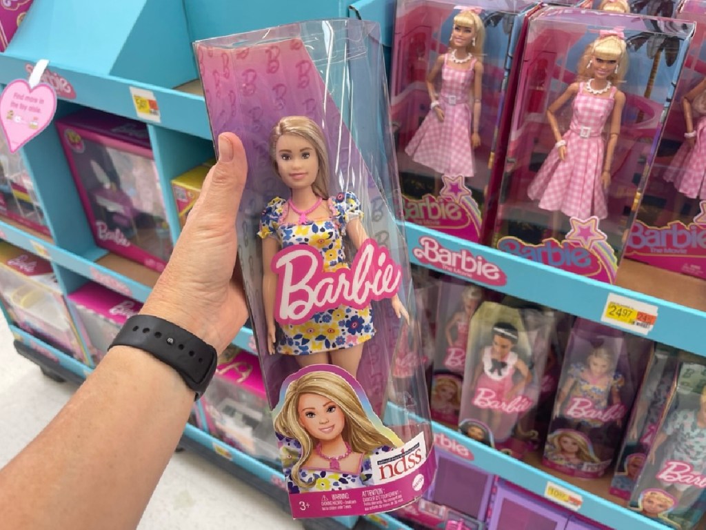 person holding Down Syndrome Barbie in store