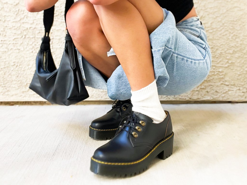 woman crouching down wearing a pair of black leather dr martens shoes
