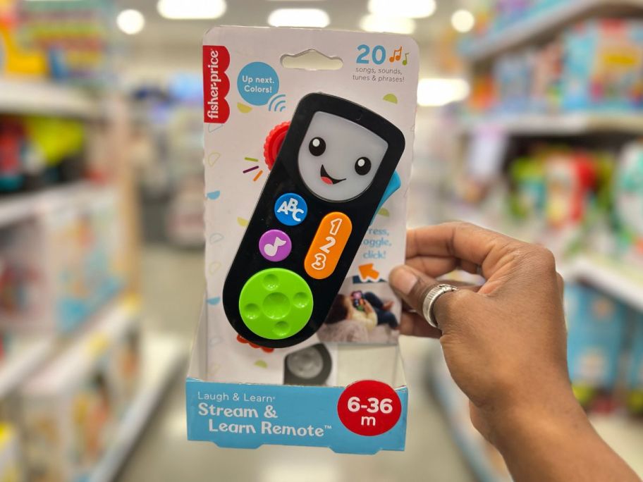 a womans hand holding an interactive toy remote learning toy