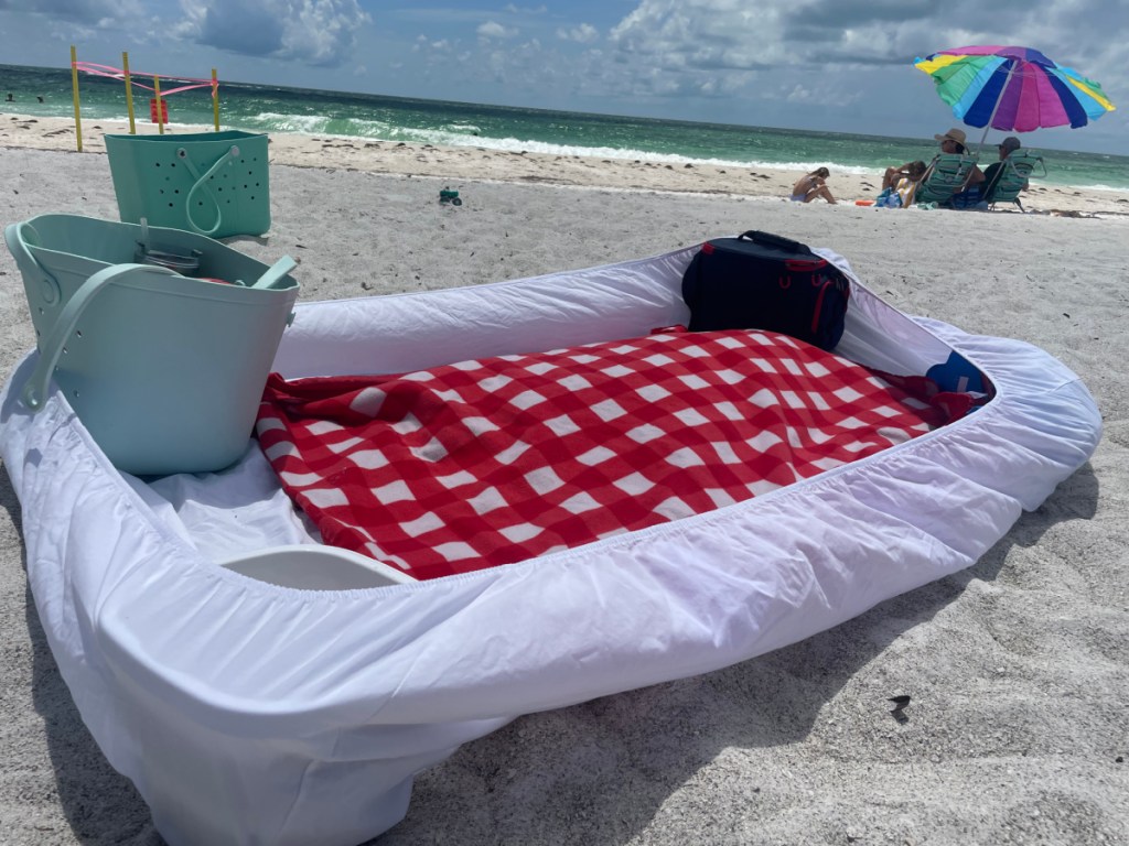 A fitted sheet being used as a beach hack at the beach to keep our sand