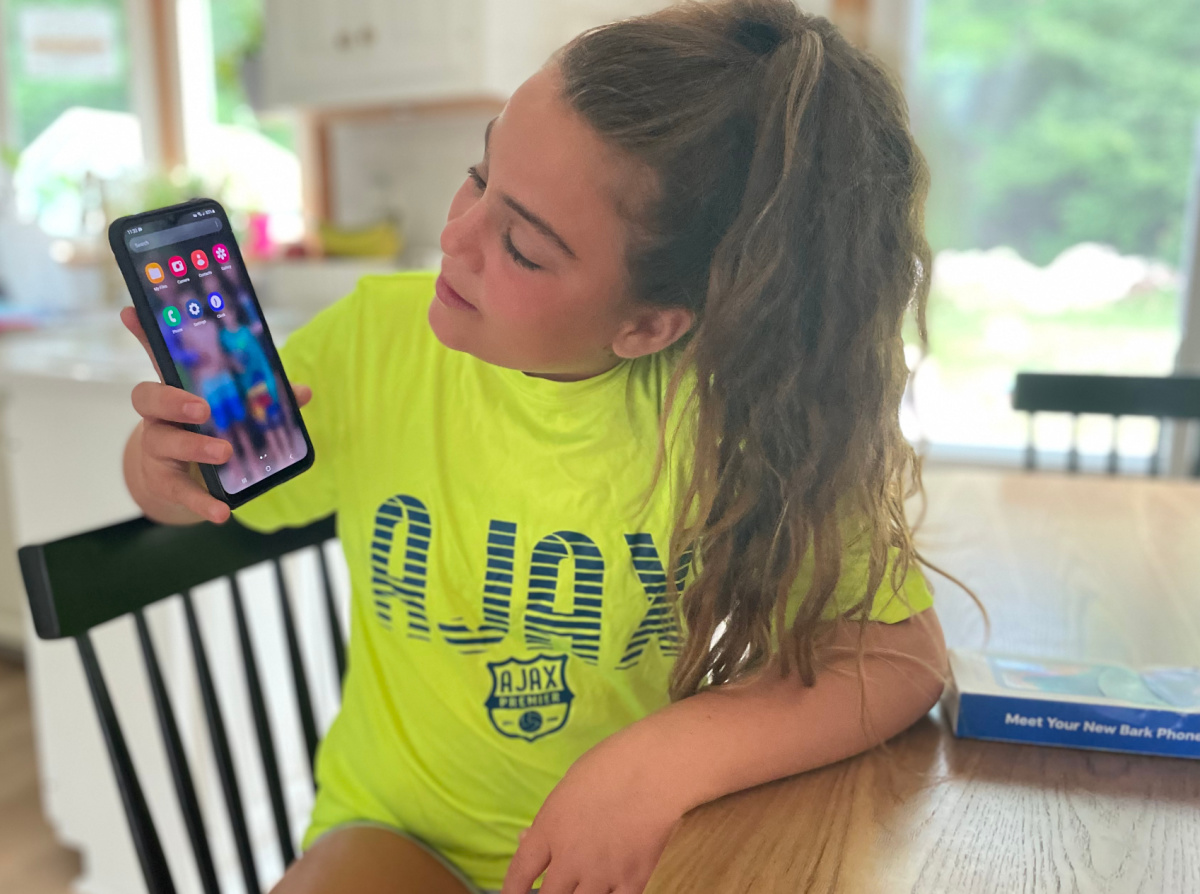Girl showing the approved apps on her Bark phone for kids