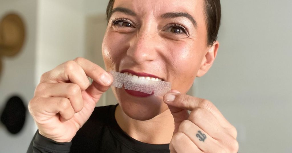 woman holding up a Gloridea Tooth Whitening Strip