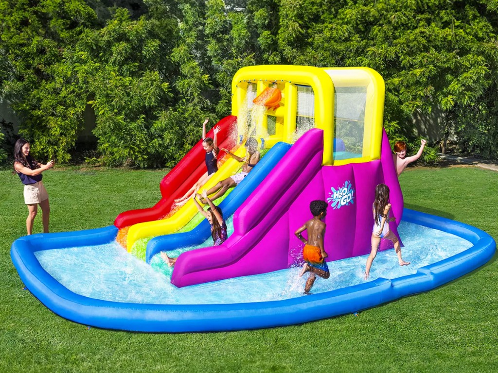 kids playing on a colorful inflatable water park on grass