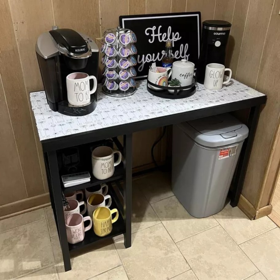 black desk with storage shelves being used as a coffee bar in a kitchen