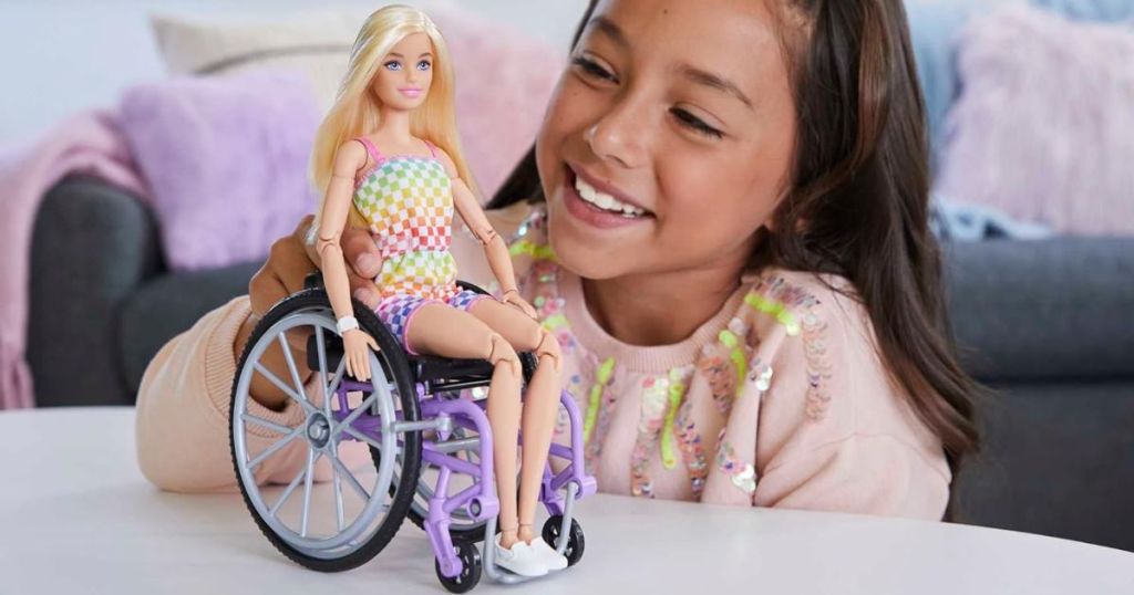 Little girl playing with a Barbie Fashionistas Dolls with Wheelchair
